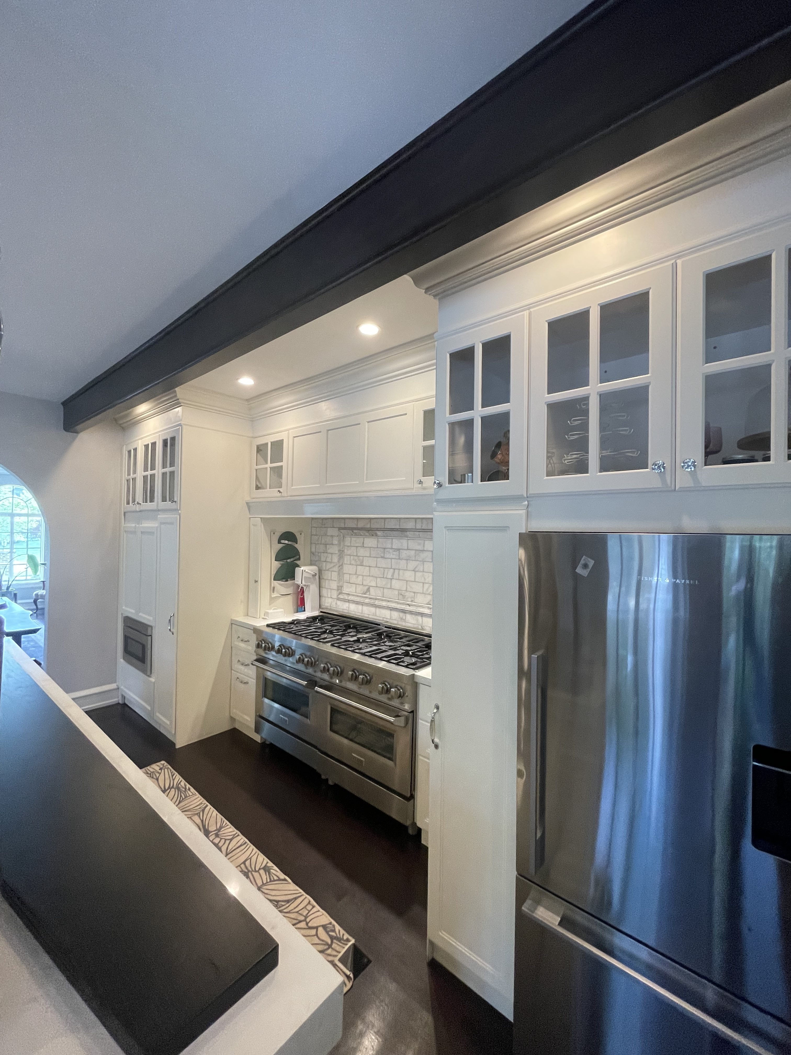 High-end kitchen remodel in La Porte, Indiana featuring custom white cabinetry, marble backsplash, and stainless steel appliances by Lomeli’s Construction